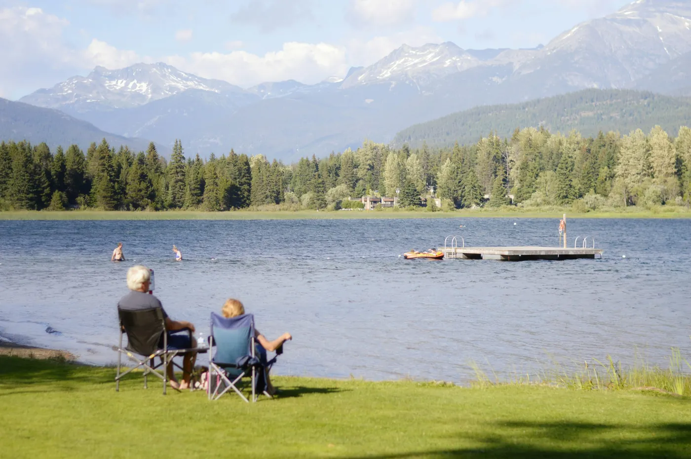 Dos personas sentadas en la hierba frente al lago