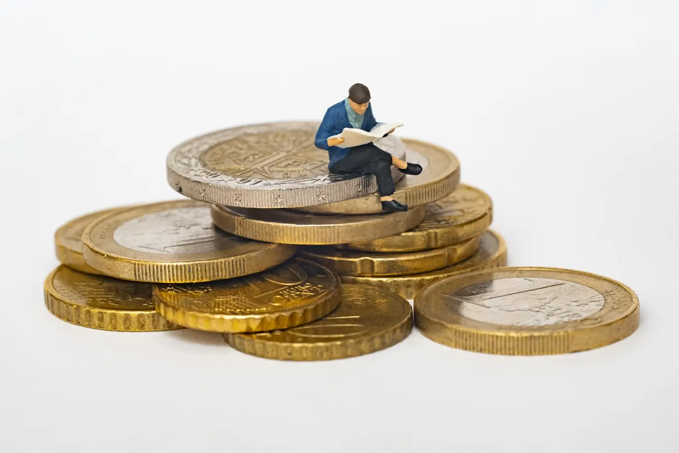Figura en miniatura sentada sobre una pila de monedas