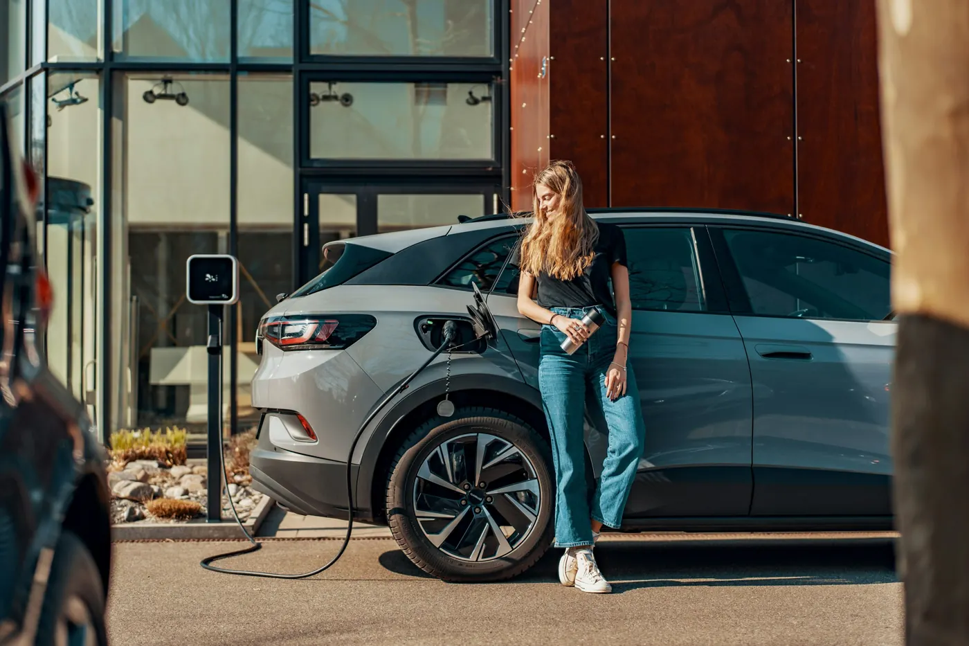 Una mujer parada junto a un coche azul