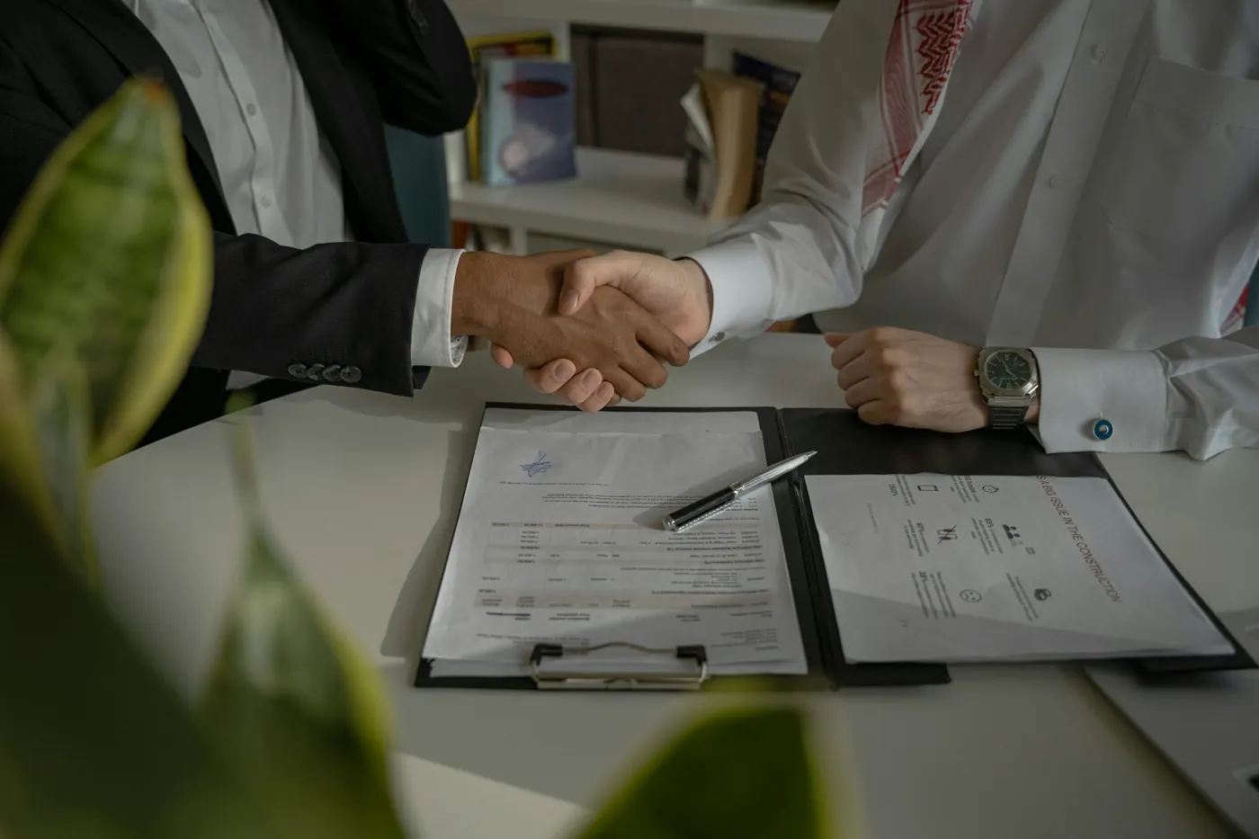 Dos personas dándose la mano sobre documentos