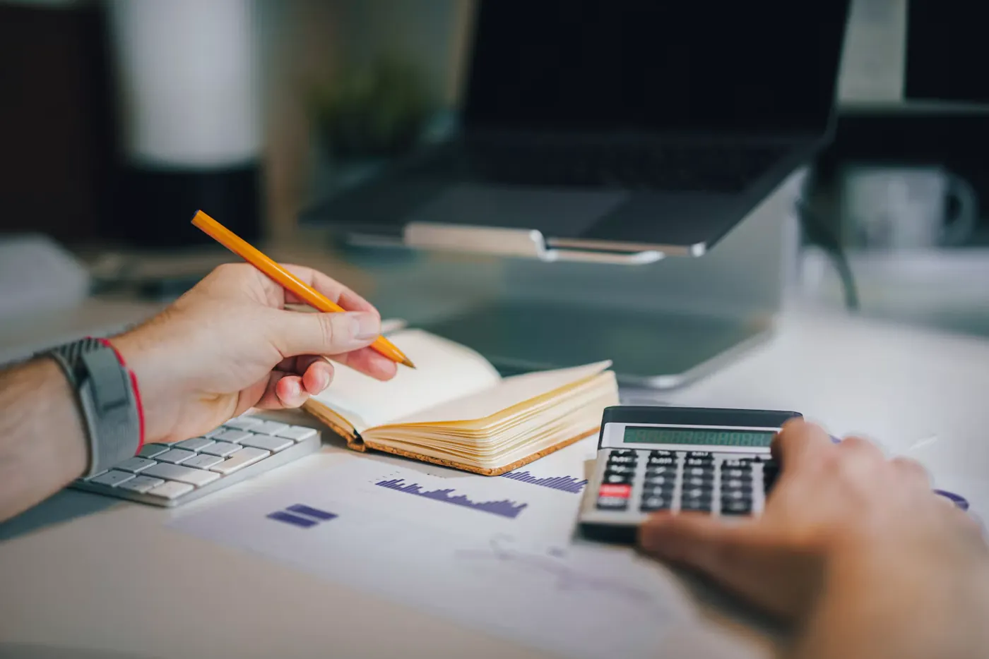 Persona revisando números con una calculadora y un cuaderno